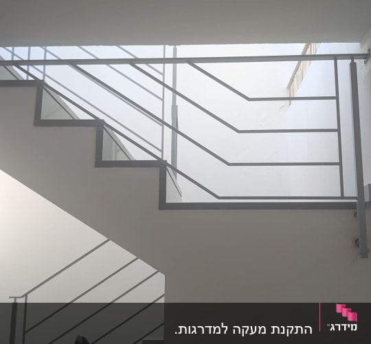 מעקה מתכת מעוצב מותקן לאורך גרם מדרגות פנימי